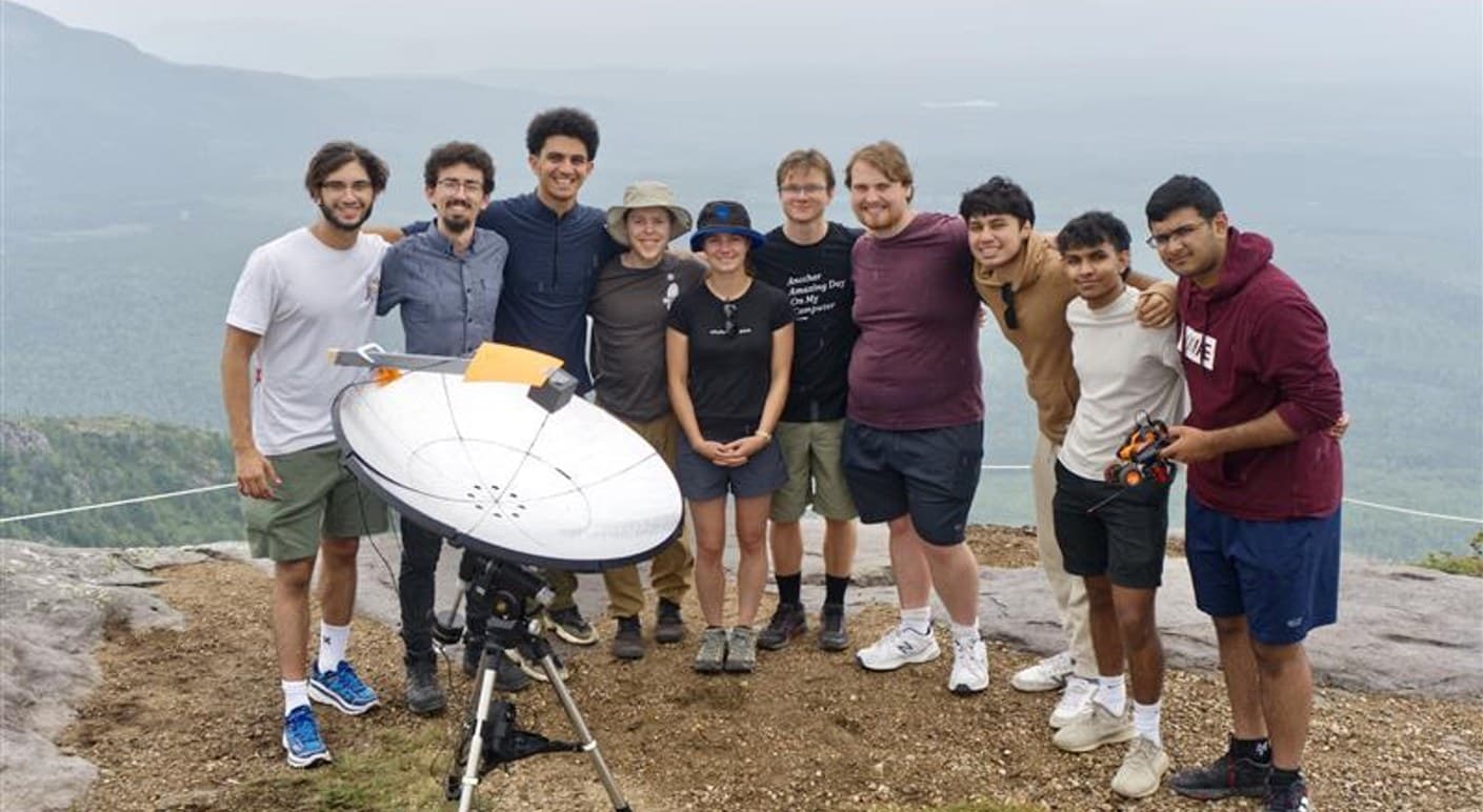 The CAN-ARX 2024 team on a rocky mountain summit, gathered around their radio telescope